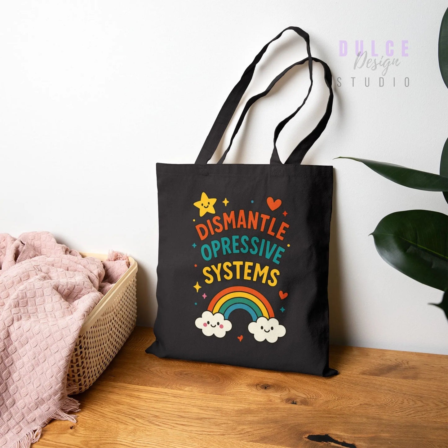 black Canvas tote bag with colorful rainbow design and text reading ‘Dismantle Oppressive Systems’ with clouds and stars