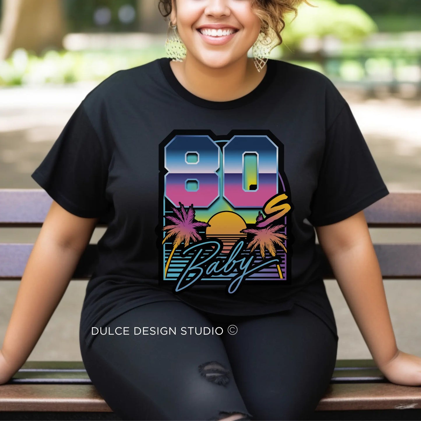 Woman wearing a Retro Vibes 80s Baby T-Shirt with sunset and palm tree graphic