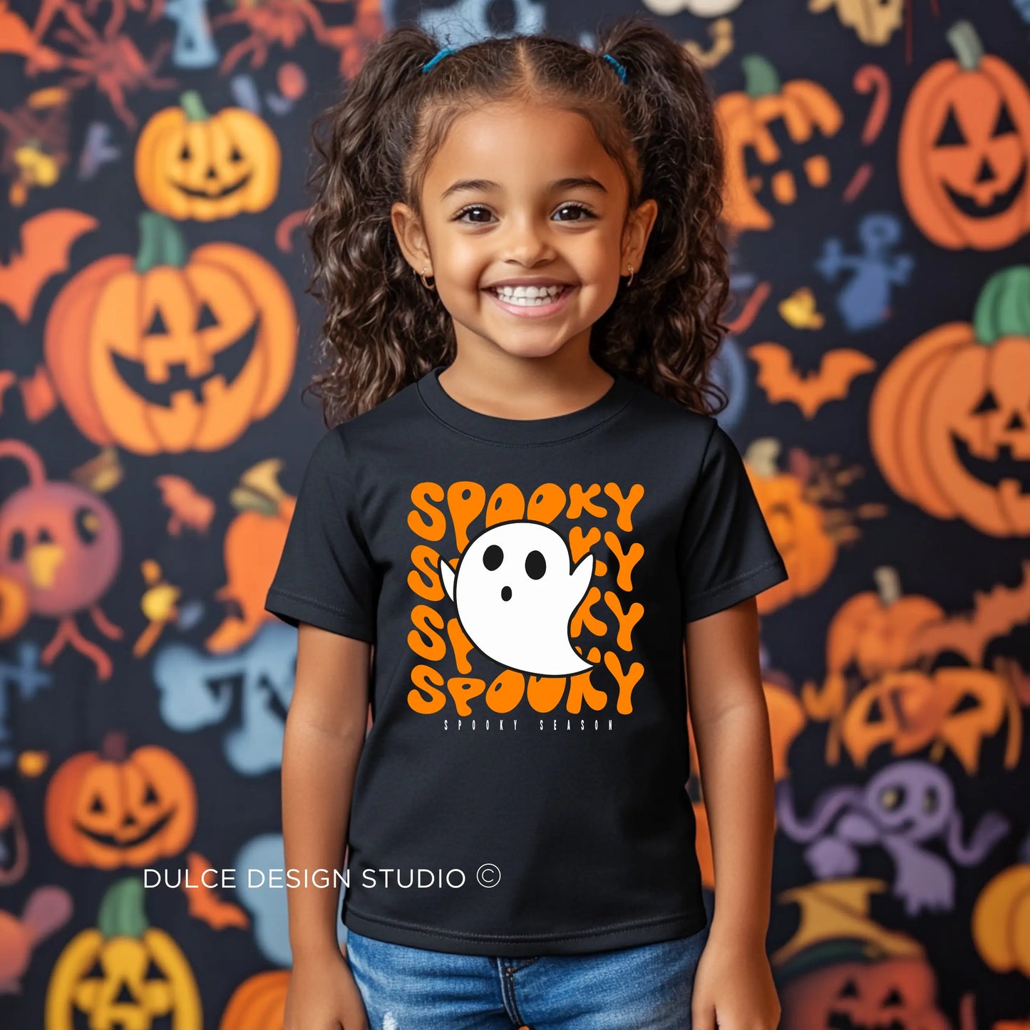 Young girl wearing a Spooky Unisex Youth T-Shirt featuring a cute ghost with the word "Spooky" in bold, fun letters, perfect for Halloween celebrations.
