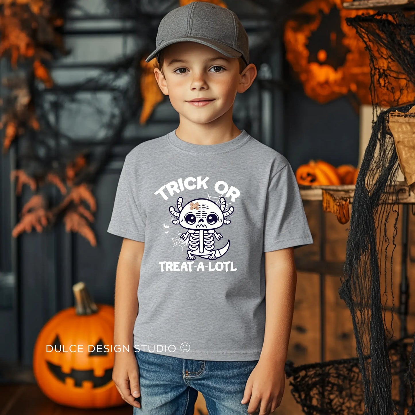 Young boy wearing a Trick or Treat A-Lotl Youth Unisex Halloween Tee with a cute axolotl skeleton design, ideal for Halloween celebrations.