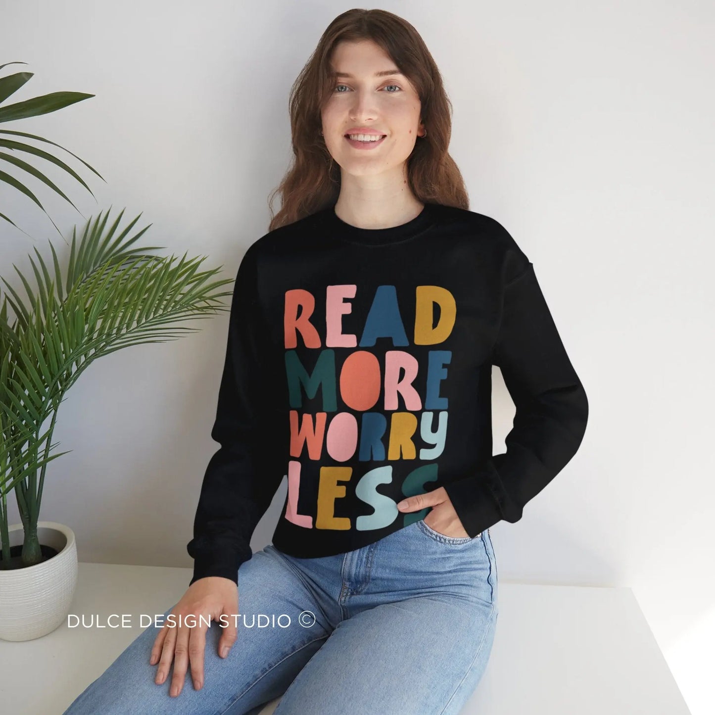 Woman wearing black sweatshirt with colorful retro text reading “Read More Worry Less” – cozy gift for readers and book lovers
