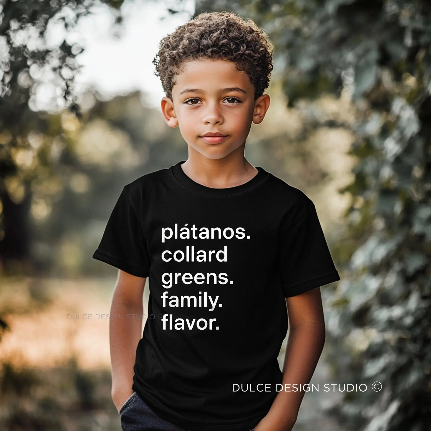 Child wearing a black t-shirt with text in a natural setting