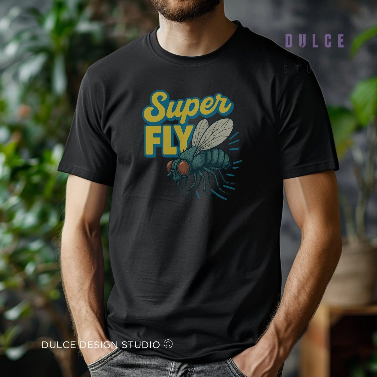Person wearing a black t-shirt with 'Super Fly' graphic design, standing in a blurred indoor setting.