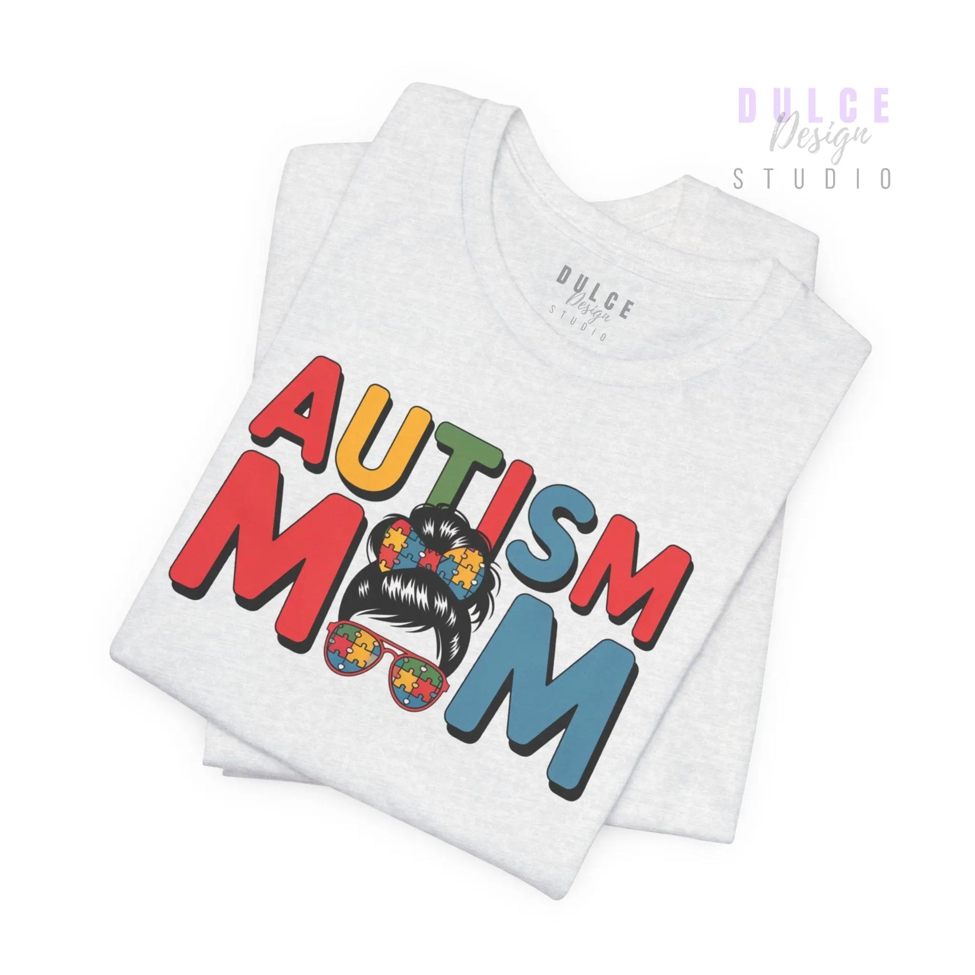 White t-shirt with 'Autism Mom' text and colorful design on a white background