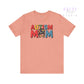 Pink t-shirt with 'AUTISM MOM' text and colorful design on a white background