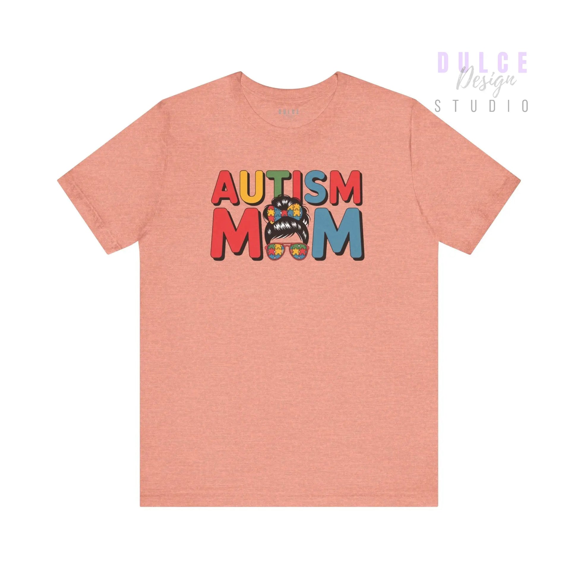 Pink t-shirt with 'AUTISM MOM' text and colorful design on a white background