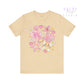 Beige t-shirt with colorful bow and shell design on a white background