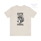 Beige t-shirt with a raccoon graphic and text 'Cute But Feral' on a white background