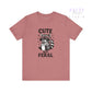 Pink t-shirt with a raccoon graphic and text 'Cute But Feral' on a white background