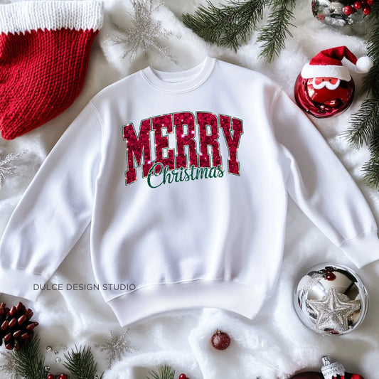 White sweatshirt with a "Merry Christmas" faux sequin design laid on a festive background with holiday decorations.