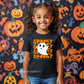 Young girl wearing a Spooky Unisex Youth T-Shirt featuring a cute ghost with the word "Spooky" in bold, fun letters, perfect for Halloween celebrations.