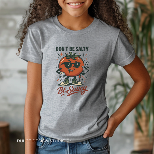 girl wearing grey t-shirt with cartoon tomato in sunglasses and text “Don’t Be Salty, Be Saucy” on athletic heather shirt