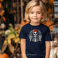 Young child wearing a Rocker Skeleton Unisex Halloween Tee with a cool skeleton wearing a red cap, perfect for a rockstar Halloween look.