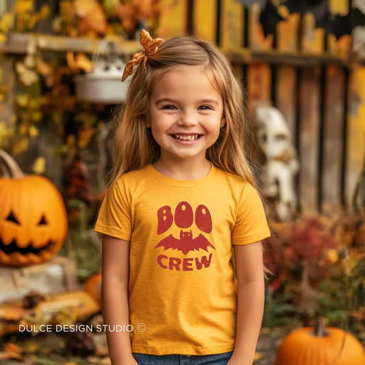 Young girl wearing a Boo Crew Unisex Youth Halloween Tee with a playful bat and "Boo Crew" text, ideal for a fun and festive Halloween look.