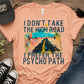 Pink t-shirt with graphic design and text on a wooden surface with shoes and a cap.