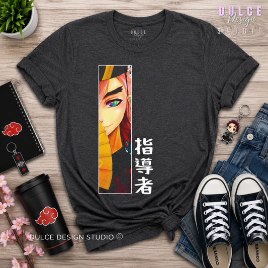 A dark heather gray graphic t-shirt featuring an anime character print and Japanese text, styled in a flat-lay arrangement on a wooden surface with jeans, sneakers, a coffee cup, and a notebook.