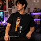 A man wearing a black graphic t-shirt featuring a vertical anime-style print of a character with pink hair and Japanese text, seated in a room with anime posters and purple ambient lighting. 'DULCE Design STUDIO' branding is visible.