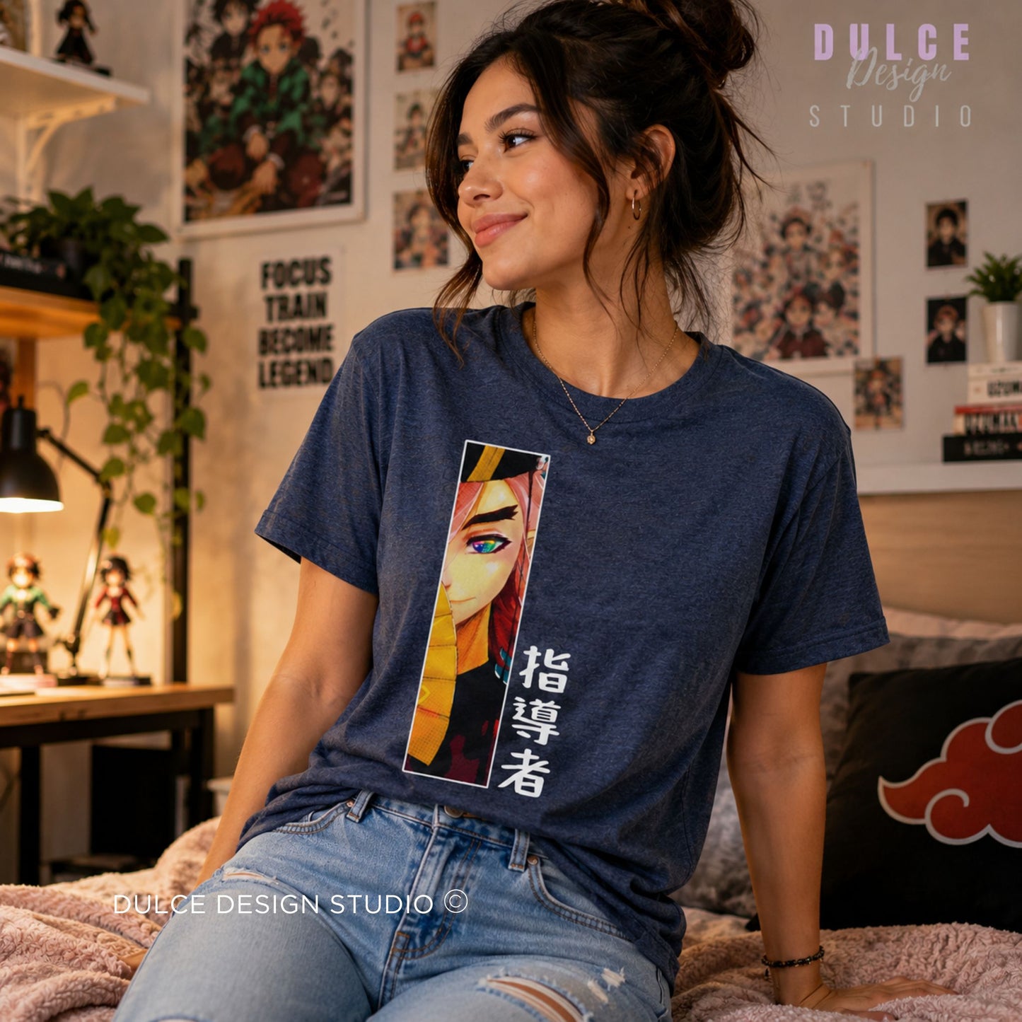 A woman wearing a navy blue graphic t-shirt with a colorful anime-style print of a character and Japanese text, sitting in a cozy, decorated room. The brand logo 'Dulce Design Studio' is visible in the top right and bottom left.