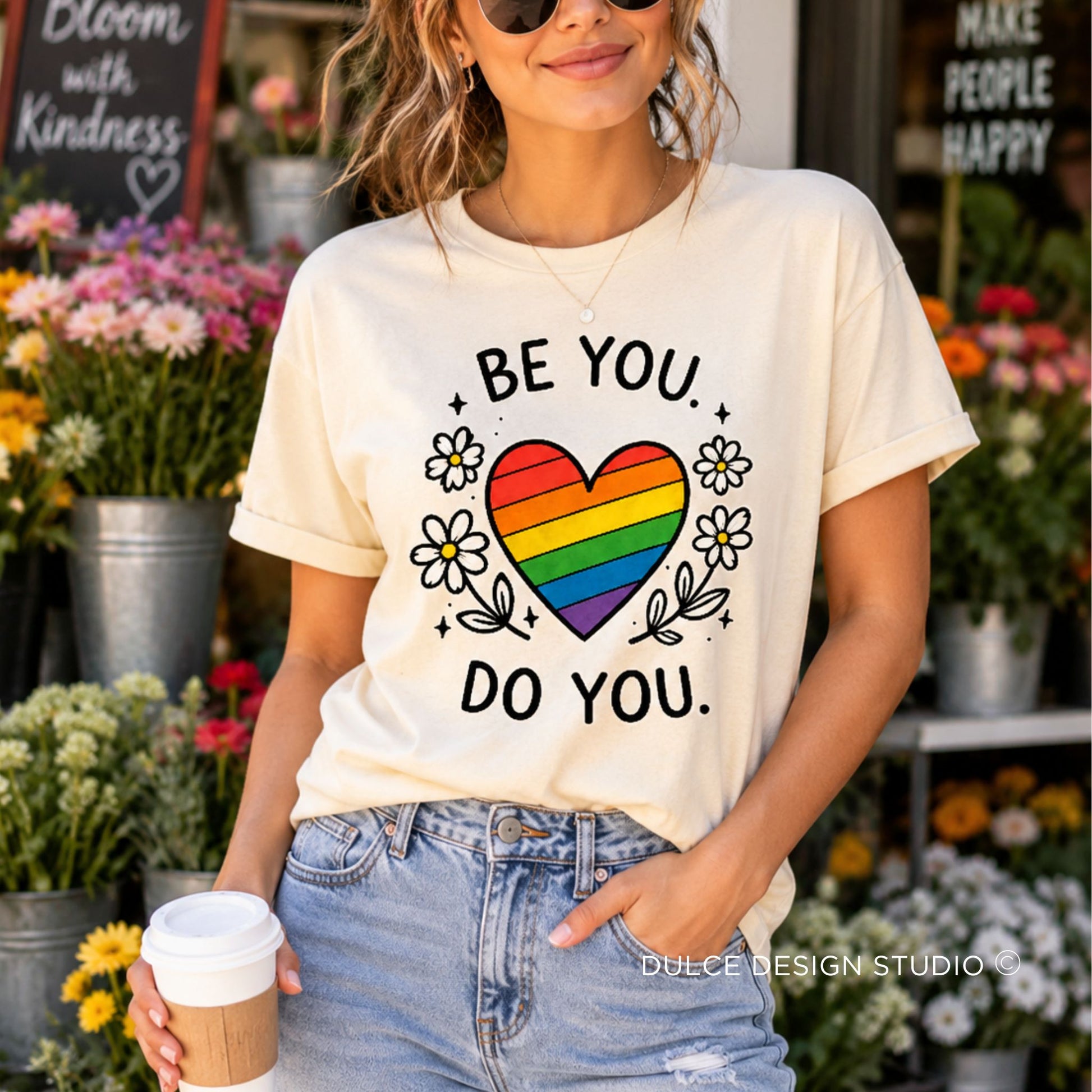 Person wearing a t-shirt with a rainbow heart and text in a flower shop