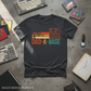 Black t-shirt with colorful text design on a concrete surface with vintage computer accessories.