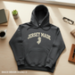 Dark gray hoodie with 'Jersey Made' text on a wooden surface with office items.
