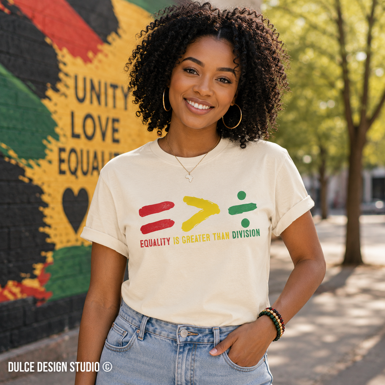 Woman wearing a t-shirt with equality-themed design in front of a colorful mural.