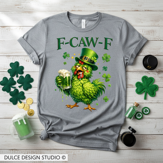 Gray t-shirt with a green rooster graphic and 'F-CAW-F' text on a wooden surface with shamrocks and coins.