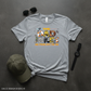 Gray t-shirt with 'The Dad Jokes Are Strong With This One' design on a dark surface with a cap, sunglasses, and watch.