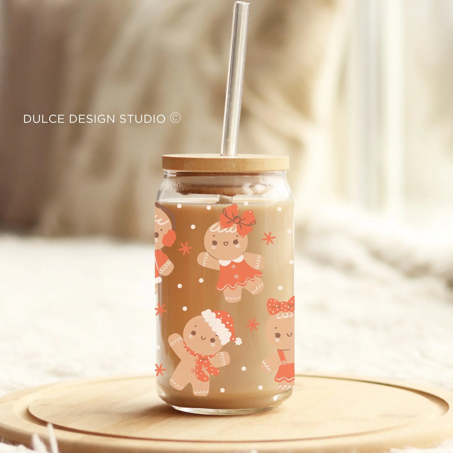 Glass tumbler with gingerbread boys and girls design, bamboo lid and straw, holiday iced coffee cup on wooden tray