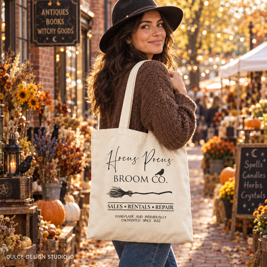 Woman carrying a natural canvas Hocus Pocus Broom Co tote at a witchy autumn market