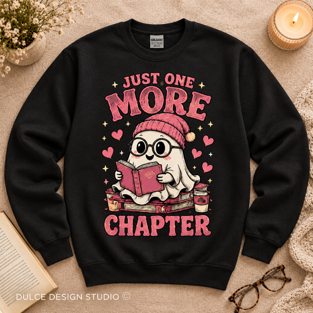 Black crewneck sweatshirt flat lay featuring a cute ghost reading a book with Just One More Chapter text.
