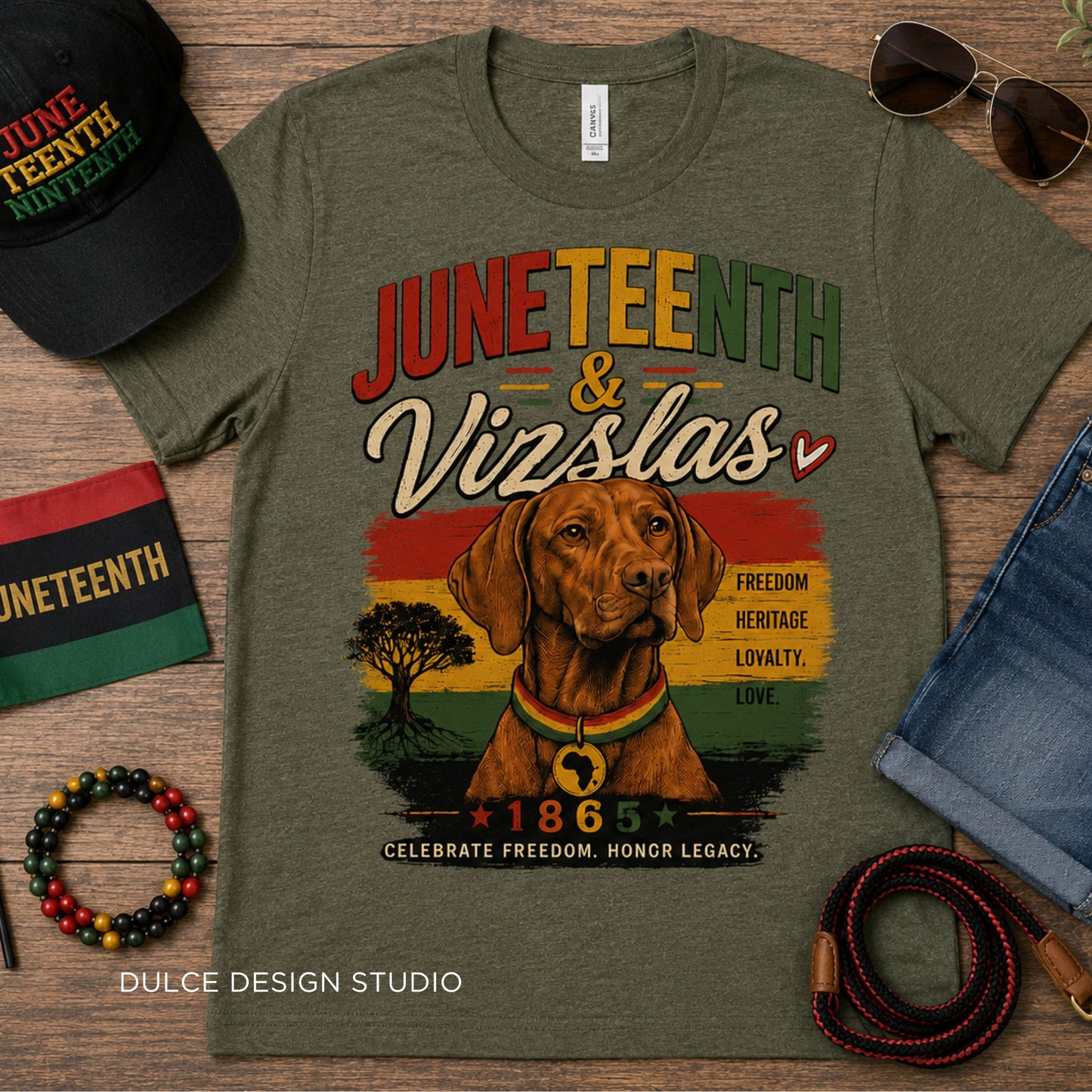 Green t-shirt with Juneteenth and Vizslas design on a wooden surface with accessories.