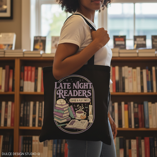 Person holding a tote bag with 'Late Night Readers' design in a library setting