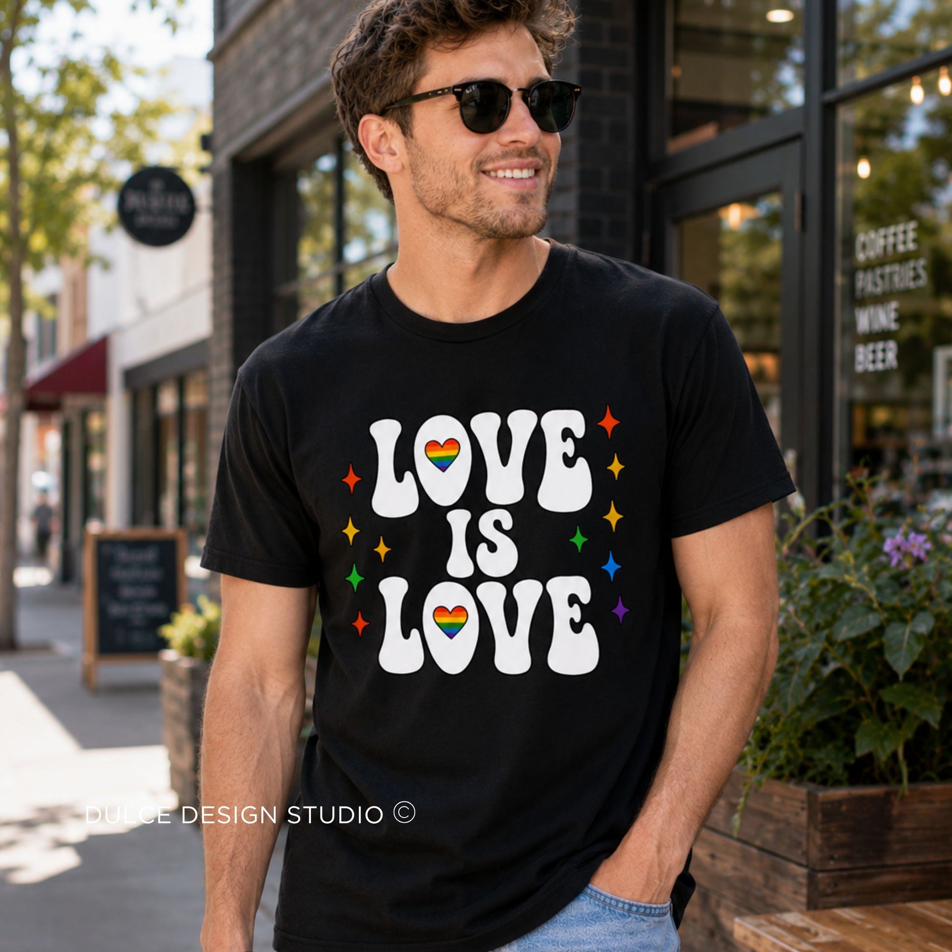 Man wearing a black t-shirt with 'LOVE IS LOVE' text and rainbow flag, standing on a street.