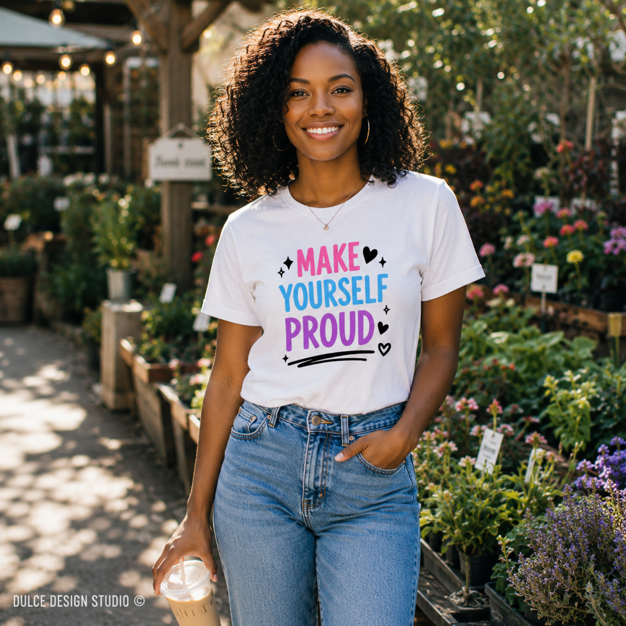 Woman wearing a 'Make Yourself Proud' t-shirt in a garden setting