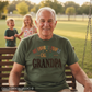 Man wearing a t-shirt with 'My favorite people call me grandpa' sitting on a swing with children in the background.