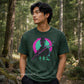 A man wearing a dark green graphic t-shirt with a stylized samurai print in pink, green, and black, standing in a forest. The watermark 'DULCE DESIGN STUDIO' is visible in the bottom left corner.