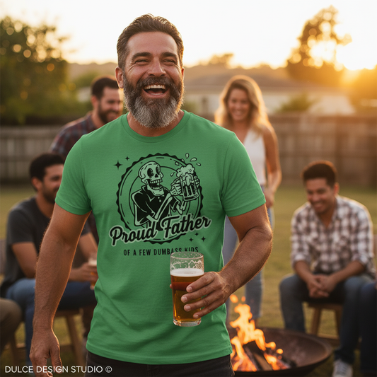 Man wearing a green t-shirt with a graphic design and text, holding a beer, standing outdoors with friends around a fire.