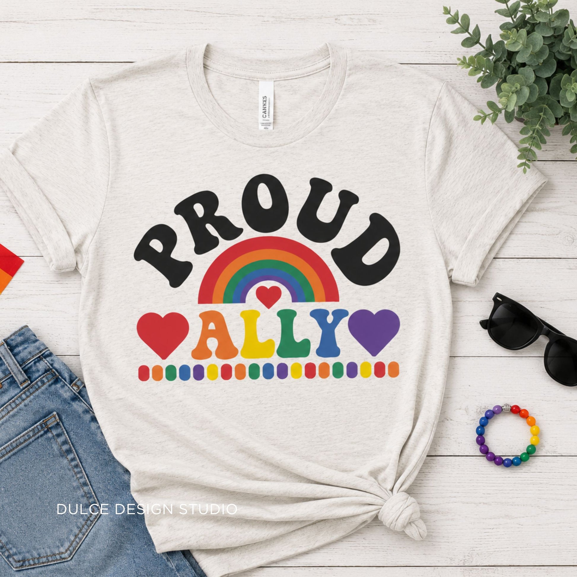 Heather Natural-shirt with rainbow design and text on a wooden surface with accessories.