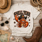White t-shirt with a lobster wearing a cowboy hat and 'Shell Year' text, surrounded by coastal items on a wooden surface.