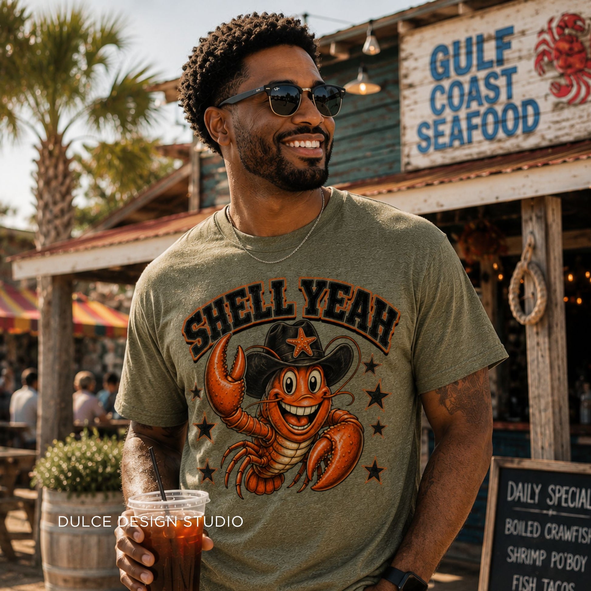 Man wearing a 'Shell Yeah' t-shirt with a cartoon lobster graphic, standing in front of a Gulf Coast Seafood restaurant.