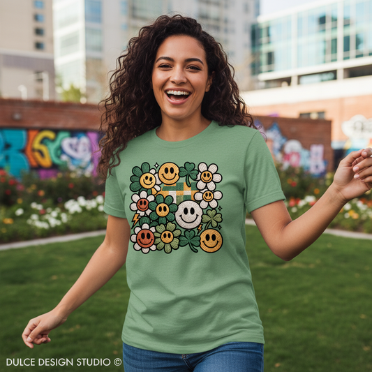 Woman wearing a green t-shirt with smiley face and flower design, standing outdoors.