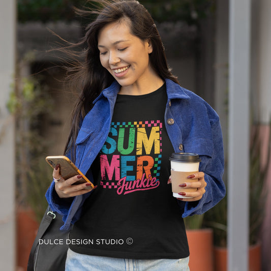 Woman wearing a black t-shirt with colorful text, holding a phone and a coffee cup, 