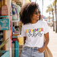Woman wearing a 'Summer vibes' t-shirt holding a drink, with palm trees and a beach store in the background.
