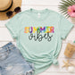 Mint green t-shirt with 'Summer vibes' text on a wooden surface with sunglasses, shorts, and a drink.