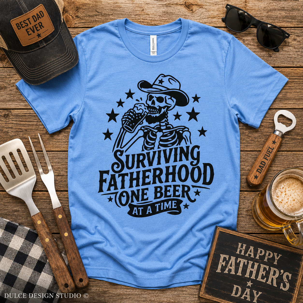 Blue t-shirt with skeleton design and text on a wooden surface with Father's Day decor.