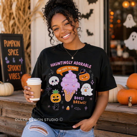 A woman wearing a black graphic t-shirt with a cute Halloween ice cream design, holding a coffee cup in a fall-themed storefront setting.
