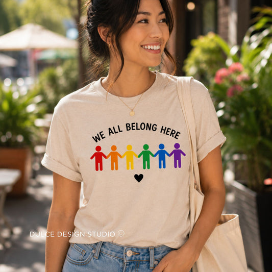 Woman wearing a t-shirt with 'We All Belong Here' message and rainbow-colored figures.
