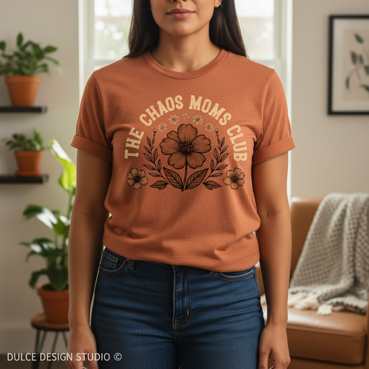 Person wearing a brown t-shirt with 'The Chaos Moms Club' design in a home setting.