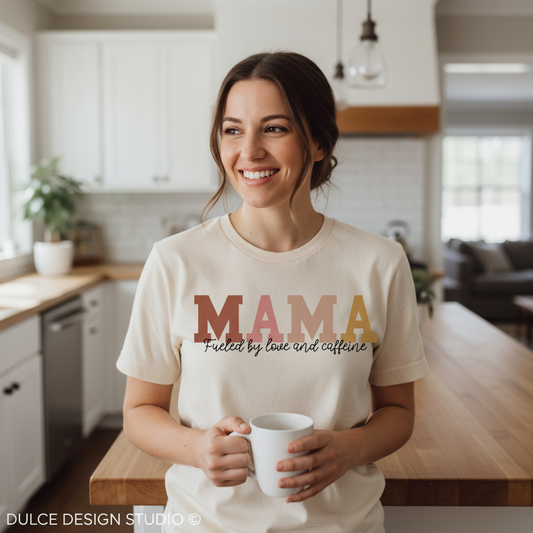 Woman in a kitchen wearing a 'MAMA' t-shirt holding a mug.